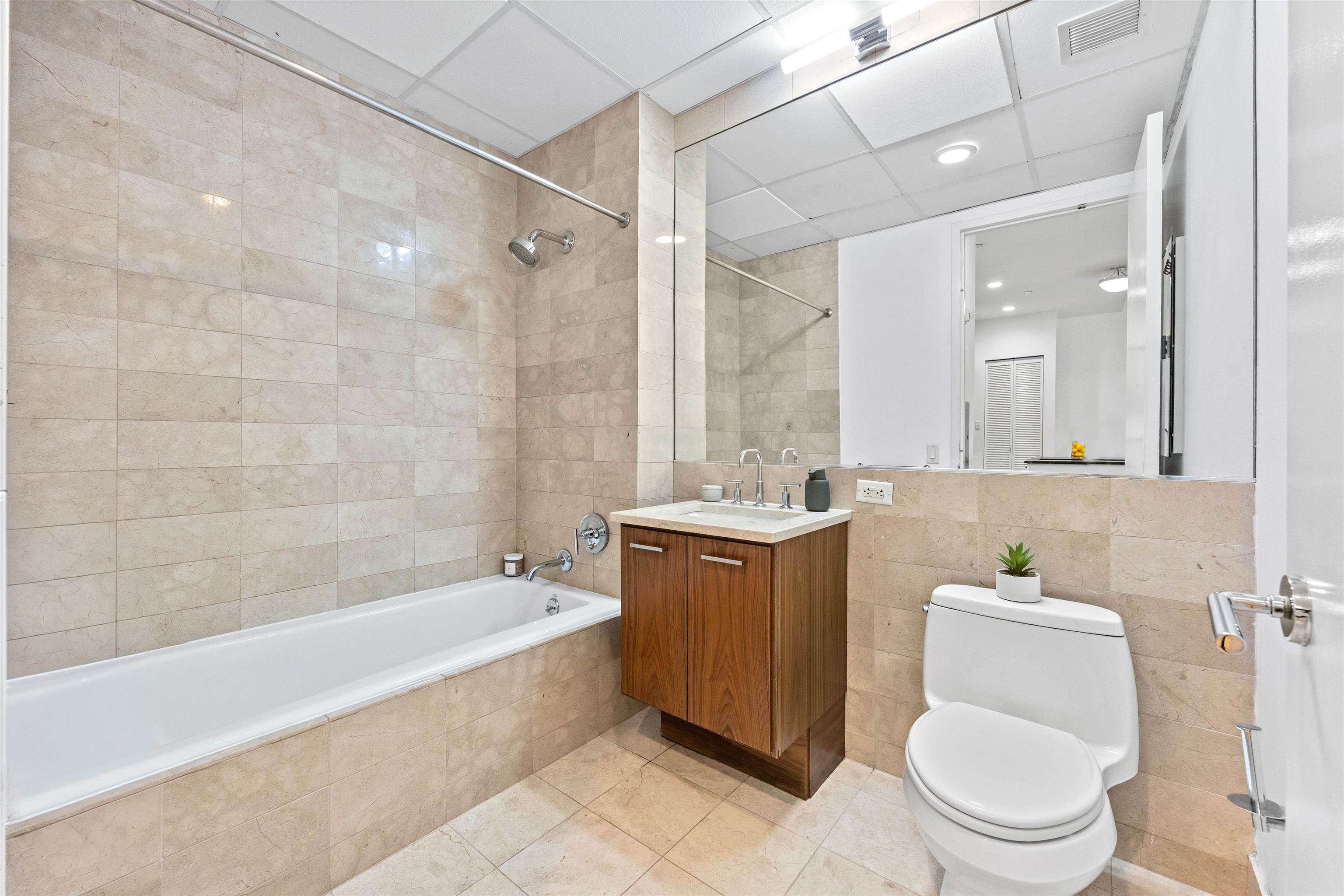 4 Beacon Way, Unit 211 Jersey City, NJ 07304 - Photo 9 of 22 a bathroom with a bathtub toilet mirror and vanity