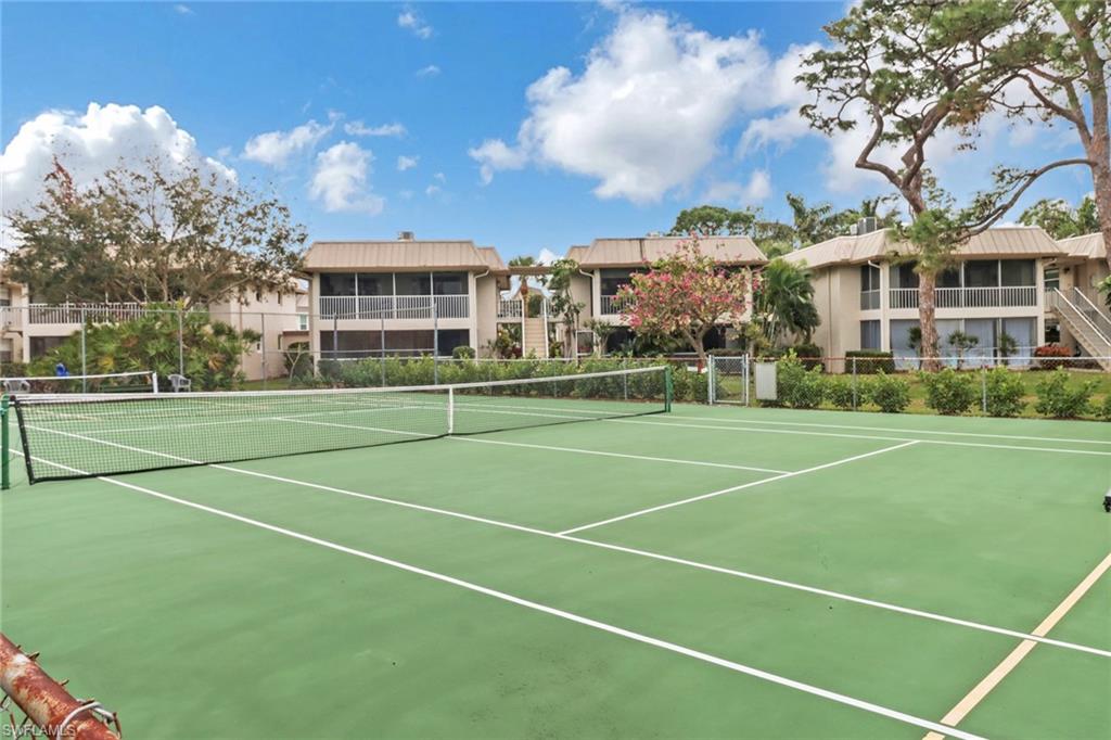 1549 Sandpiper Street, Unit 1 Naples, FL 34102 - Photo 14 of 16 a view of a tennis ground with large trees