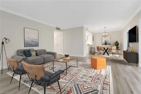 a living room with furniture a flat screen tv and kitchen view