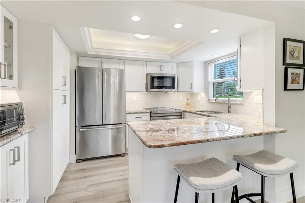 1549 Sandpiper Street, Unit 1 Naples, FL 34102 - Photo 4 of 16 a kitchen with a refrigerator and a stove top oven