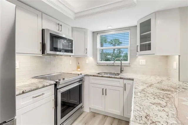 a kitchen with granite countertop stainless steel appliances white cabinets granite counter tops and a window
