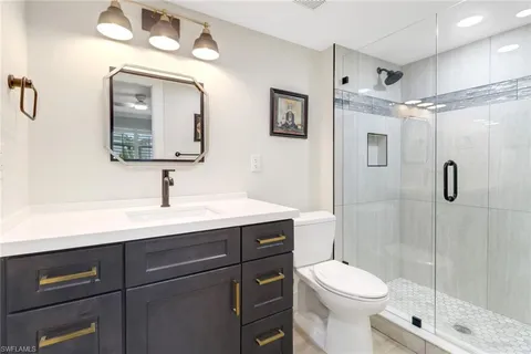 a bathroom with a toilet a sink a mirror and shower