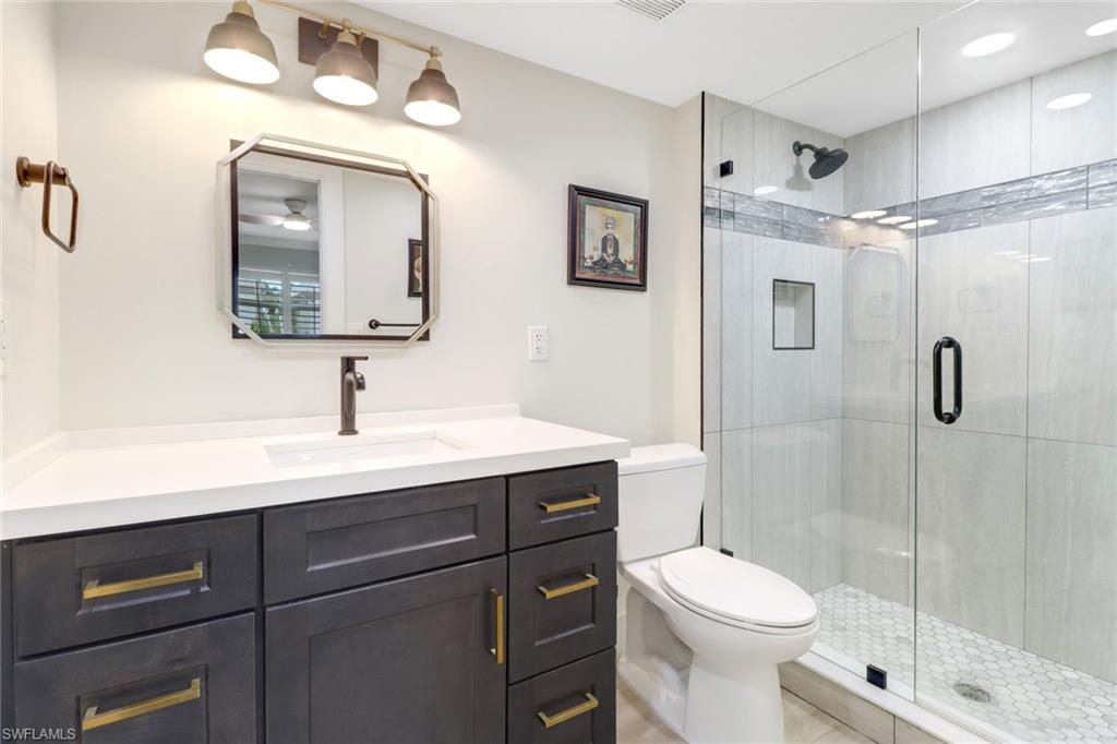 1549 Sandpiper Street, Unit 1 Naples, FL 34102 - Photo 7 of 16 a bathroom with a toilet a sink a mirror and shower