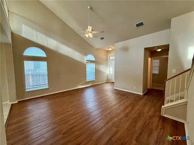 a view of an empty room with window and wooden floor
