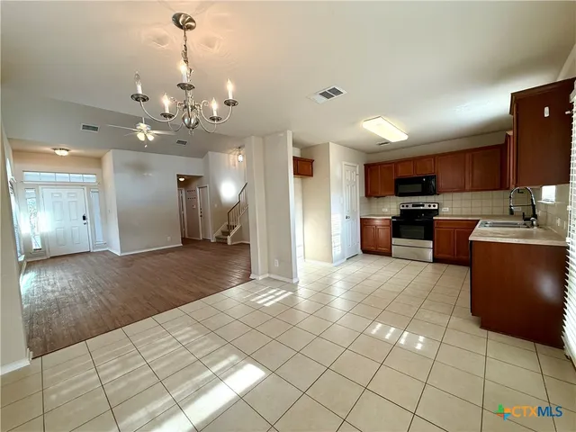 a view of a kitchen with kitchen island stainless steel appliances refrigerator stove microwave and cabinets
