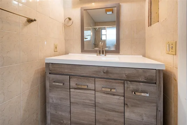 a bathroom with a granite countertop sink a mirror and shower