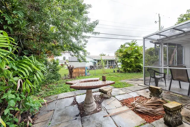 a view of a backyard with table and chairs potted plants and large tree