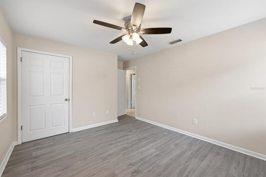 1439 Wilson Road Clearwater, FL 33755 - Photo 17 of 26 an empty room with wooden floor ceiling fan and windows