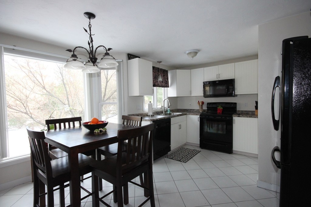 1 Country Side Road, Unit 1 Bellingham, MA 02019 - Photo 3 of 20 a kitchen with a dining table chairs appliances and cabinets