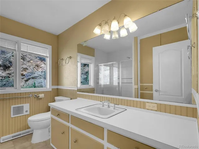 a bathroom with a granite countertop sink a toilet a mirror and a tub