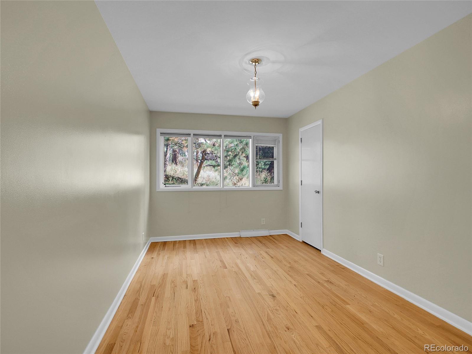 28449 Douglas Park Road Evergreen, CO 80439 - Photo 22 of 25 an empty room with wooden floor chandelier and windows