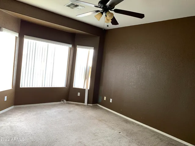 an empty room with windows and fan