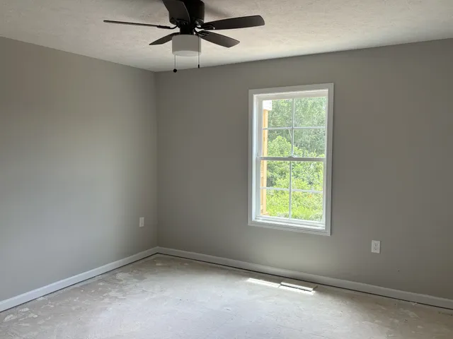 an empty room with a window and a fan