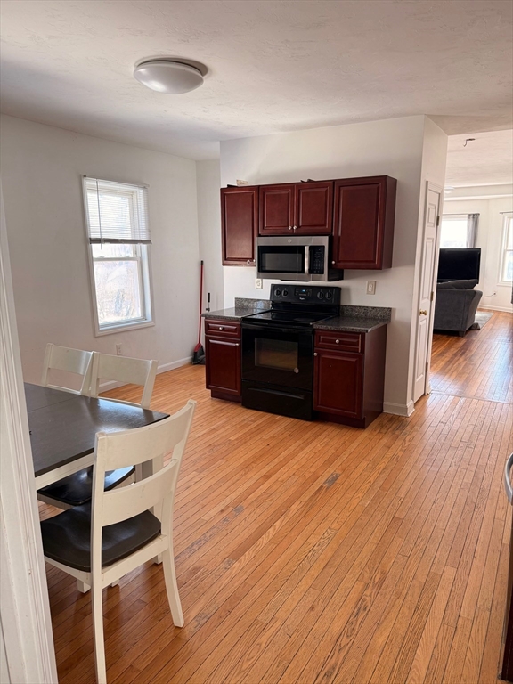 1442 Main Street, Unit 3 Worcester, MA 01603 - Photo 3 of 9 a kitchen with stainless steel appliances wooden floors and wooden cabinets