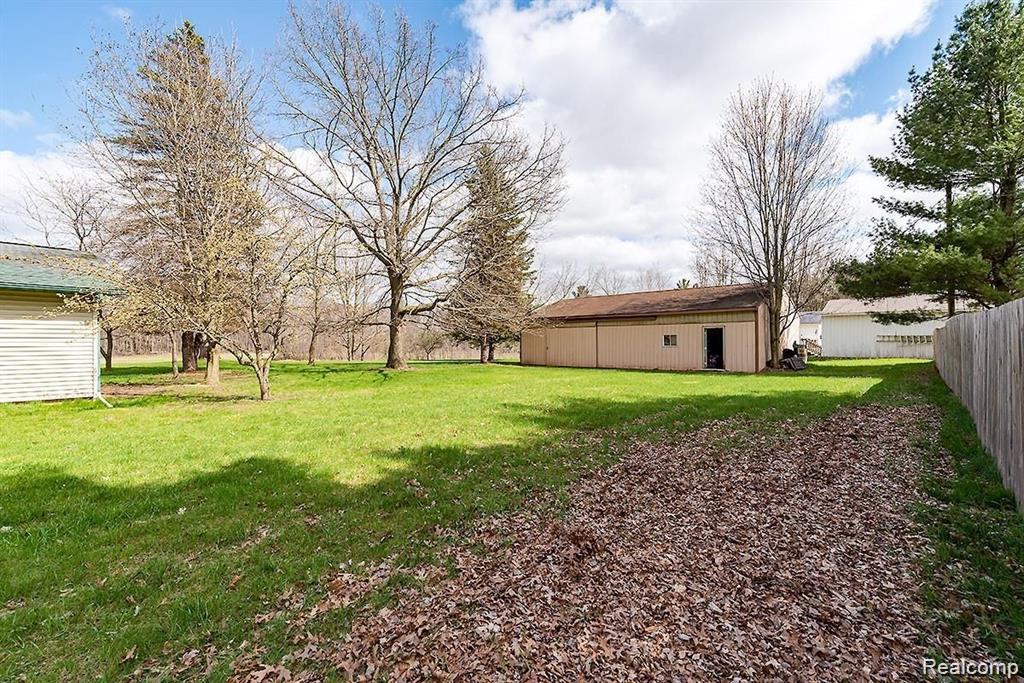 140 Larson Road Attica, MI 48412 - Photo 7 of 41 Expansive green lawn with mature trees and a detached outbuilding