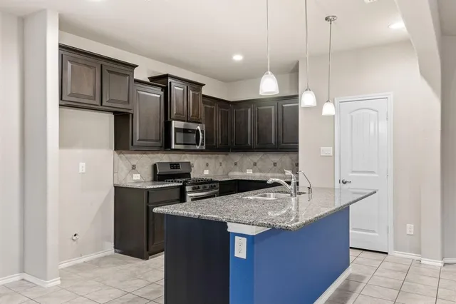 a kitchen with kitchen island granite countertop a sink cabinets and stainless steel appliances