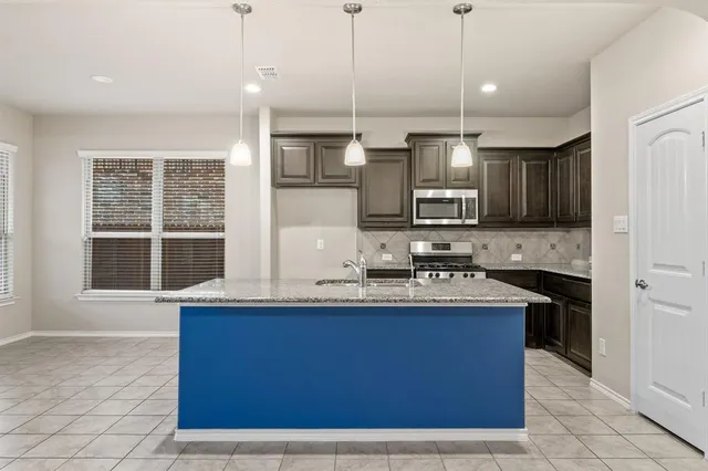 a kitchen with stainless steel appliances granite countertop a stove a sink and a microwave