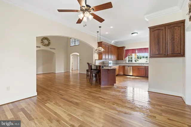 a open kitchen with stainless steel appliances granite countertop a refrigerator a stove and a wooden floors