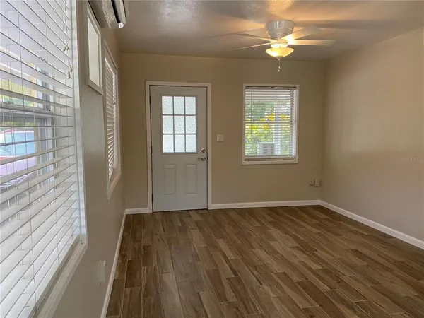 a view of an empty room with wooden floor and a window