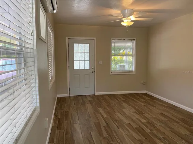 a view of an empty room with wooden floor and a window
