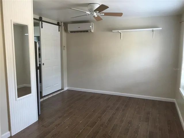 a view of an empty room with wooden floor and a ceiling fan