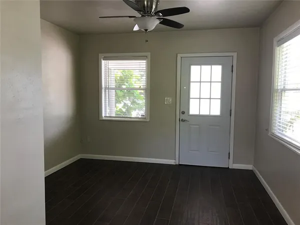 a view of an empty room with wooden floor and a window