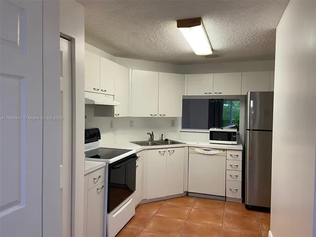 a kitchen with a sink white cabinets and white appliances
