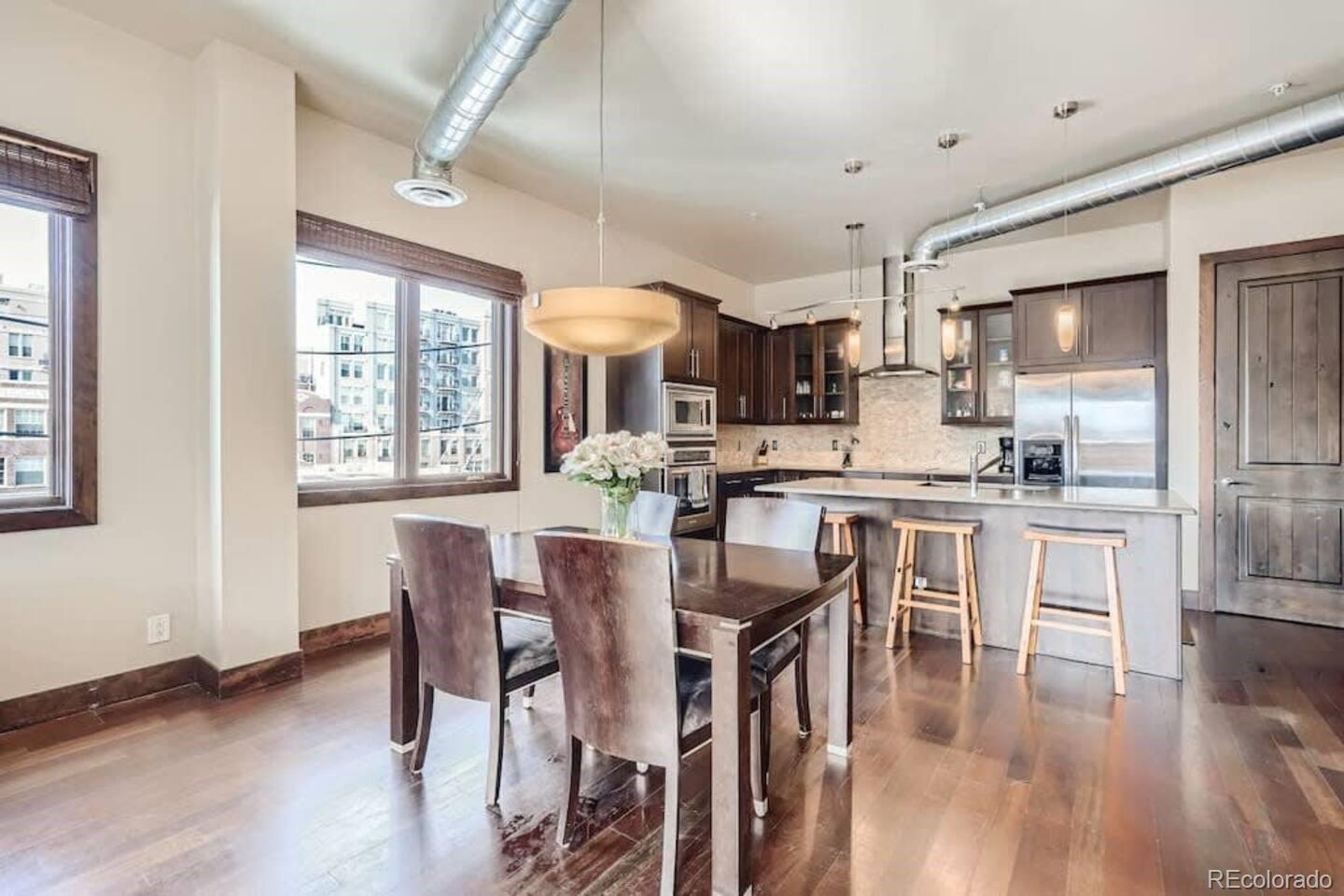 2101 Larimer Street, Unit 303 Denver, CO 80205 - Photo 6 of 21 a kitchen with stainless steel appliances kitchen island granite countertop a dining table chairs and granite counter tops