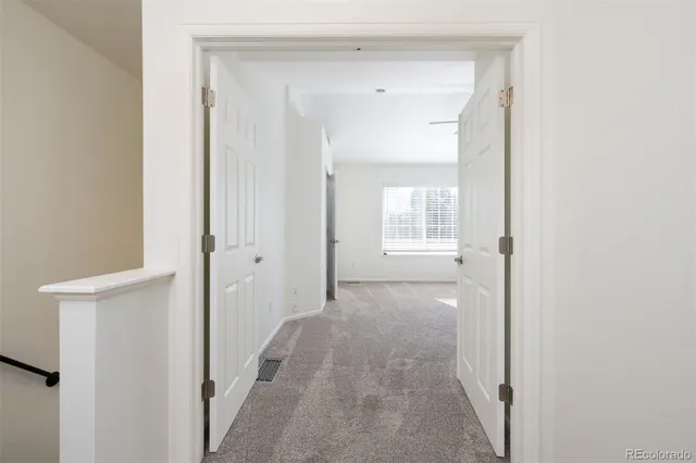 a view of a hallway with white walls and stairs