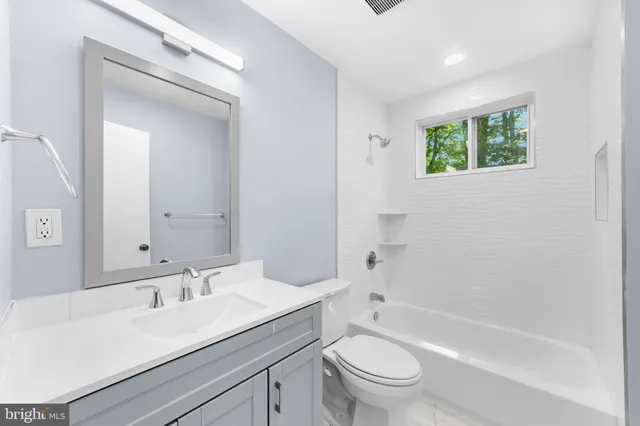 a bathroom with a bathtub shower sink vanity mirror and toilet