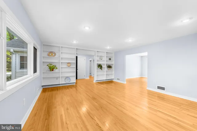 a view of an empty room with window and wooden floor