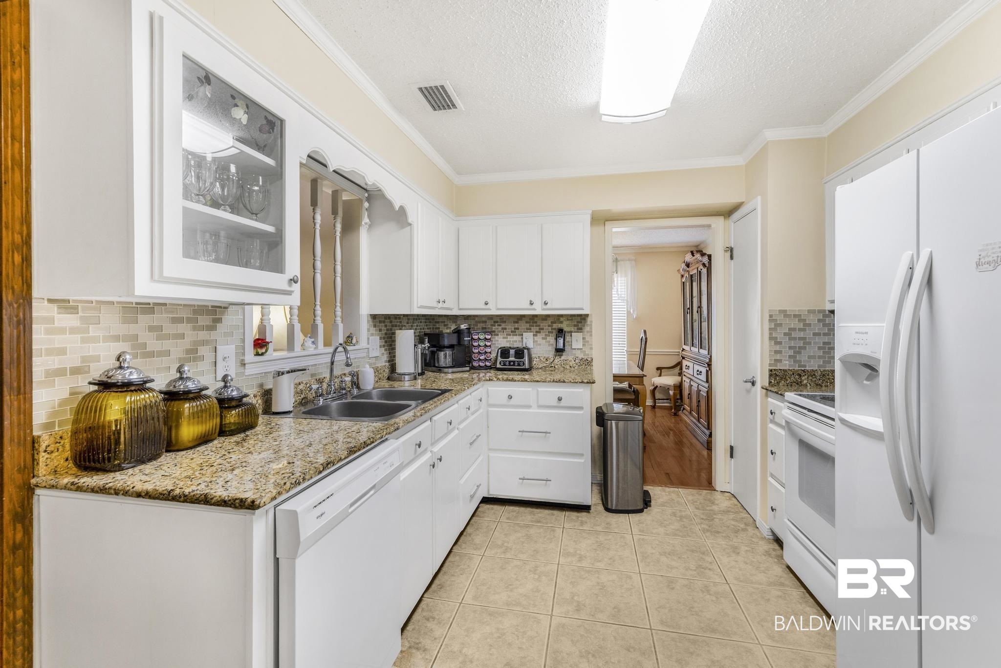 10207 Plantation Drive Daphne, AL 36526 - Photo 36 of 48 Kitchen with a textured ceiling, white appliances, white cabinets, glass fronted cabinets, and light tile patterned flooring