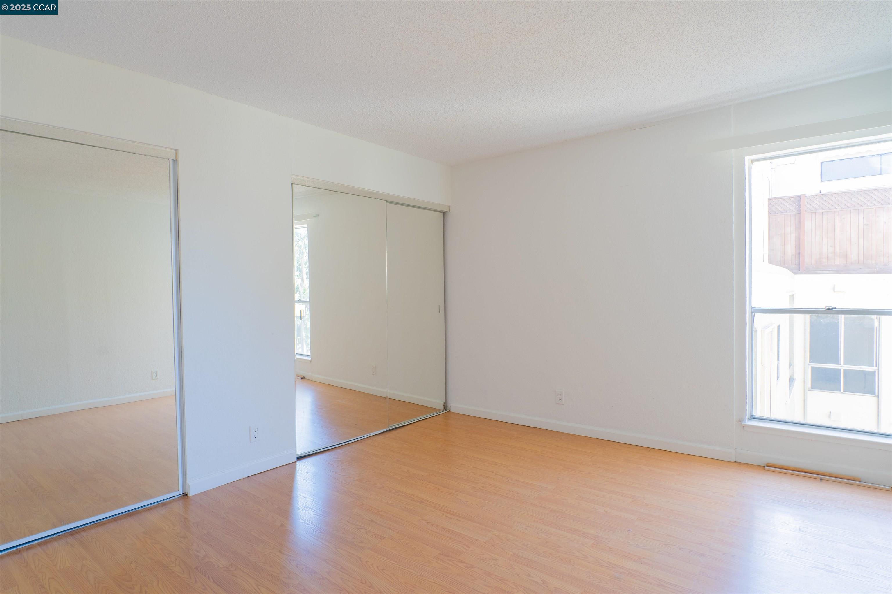 466 Crescent Street, Unit 306 Oakland, CA 94610 - Photo 16 of 26 an empty room with wooden floor and windows