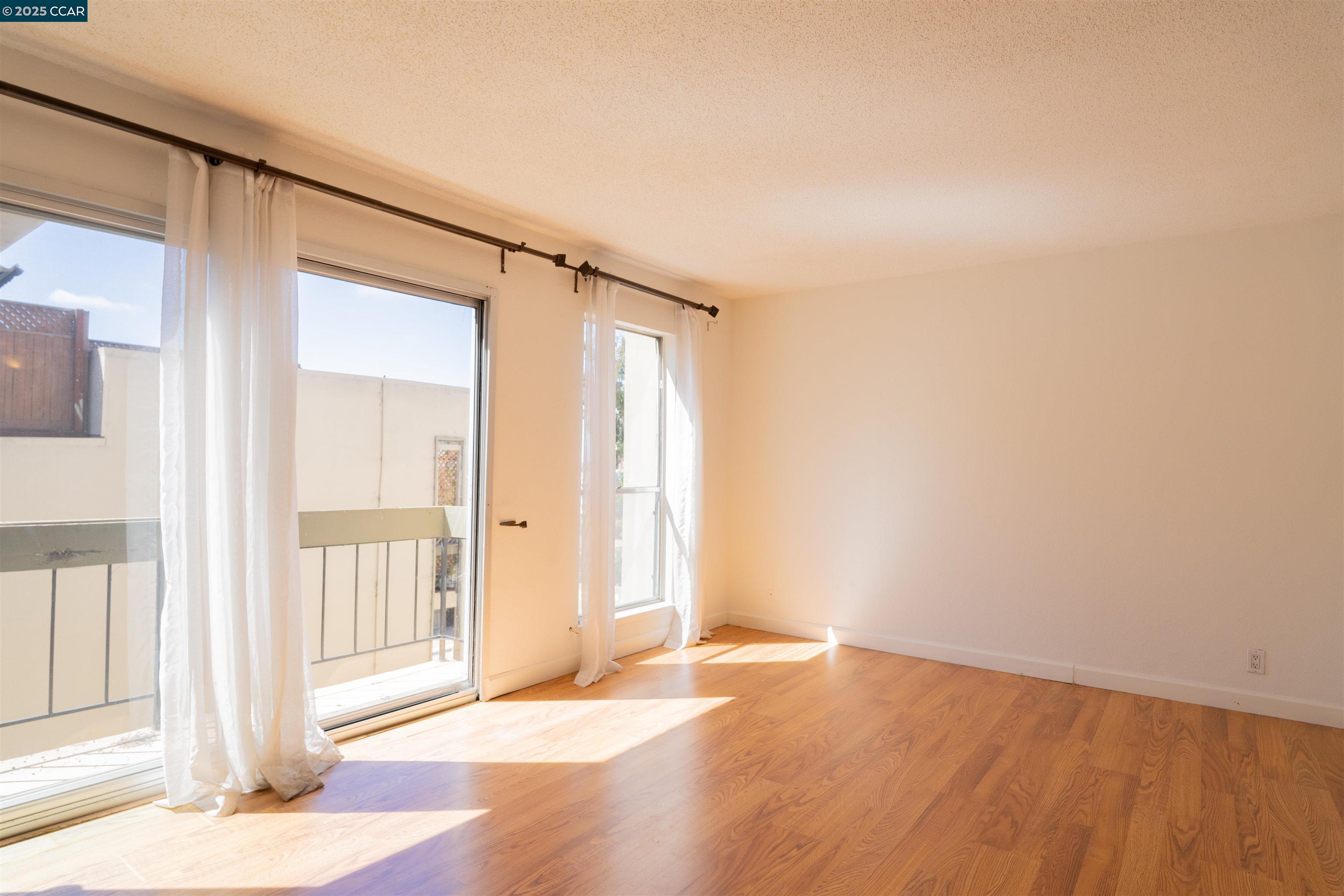 466 Crescent Street, Unit 306 Oakland, CA 94610 - Photo 2 of 26 an empty room with wooden floor and windows
