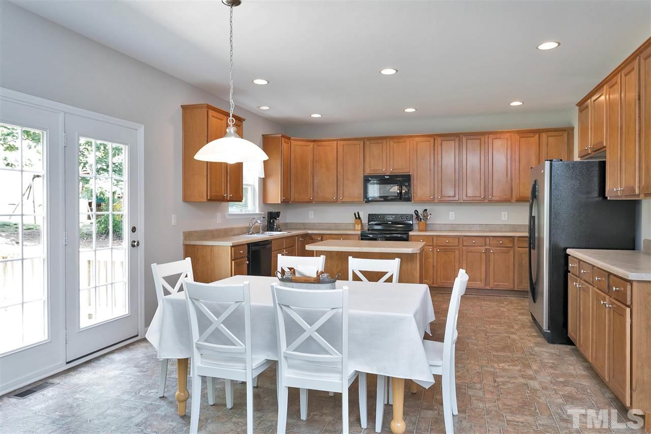 118 Key Biscayne Court Raleigh, NC 27603 - Photo 13 of 30 a kitchen with stainless steel appliances granite countertop a stove a refrigerator a kitchen island a dining table and chairs