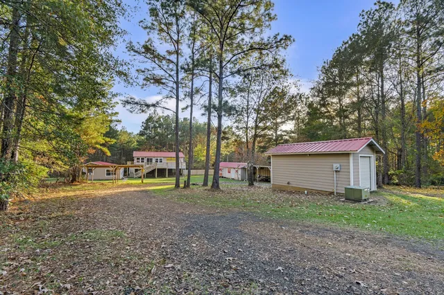 a view of a house with large trees and a small yard