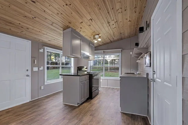 a kitchen with stainless steel appliances granite countertop a refrigerator a sink dishwasher a stove and white countertops with wooden floor