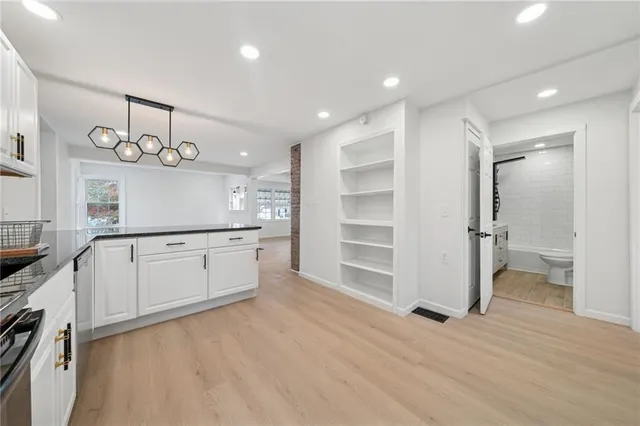 a kitchen with white cabinets and wooden floor