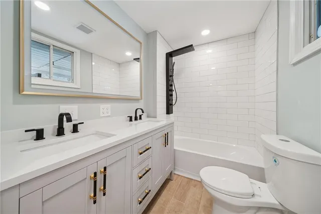 a bathroom with a granite countertop sink a toilet a mirror and shower