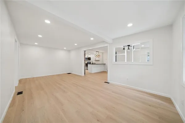 a view of empty room with kitchen and window