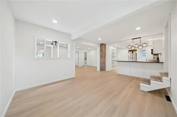 a view of a kitchen with kitchen island a refrigerator wooden floor and a sink