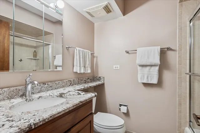 a bathroom with a granite countertop sink a toilet and mirror