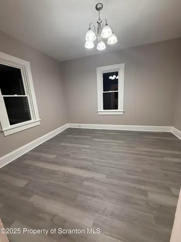 a view of an empty room with a window and chandelier