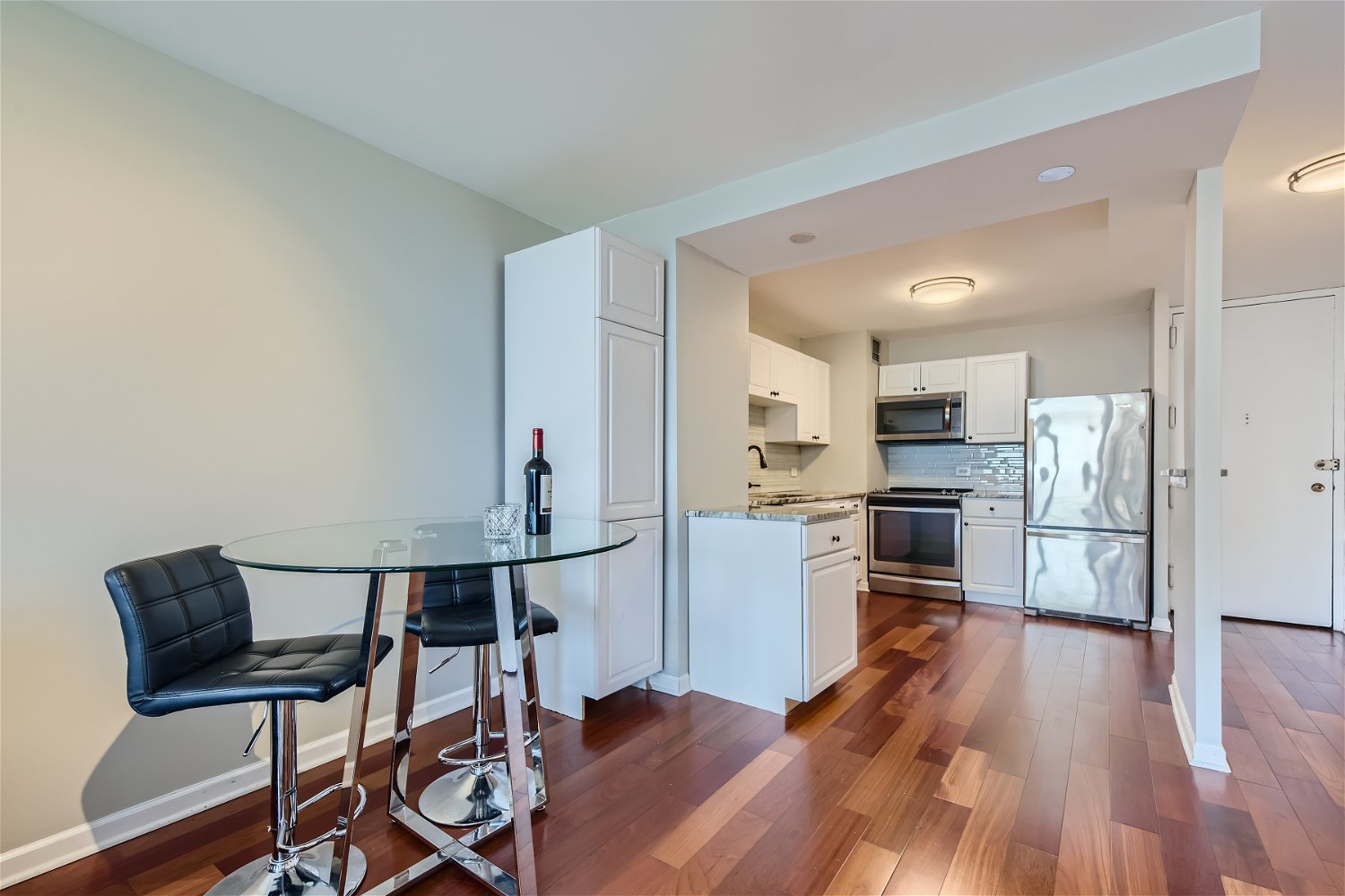 1636 North Wells Street, Unit 1505 Chicago, IL 60614 - Photo 7 of 21 a kitchen with stainless steel appliances a refrigerator a stove top oven and a dining table with wooden floor