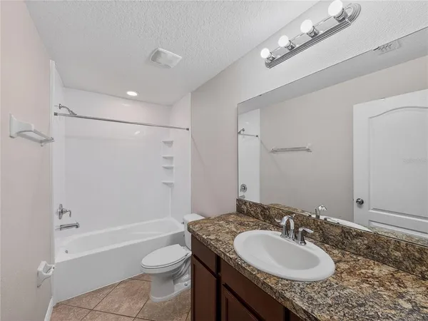 a bathroom with a granite countertop sink toilet a mirror a bathtub and shower