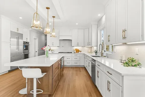 a kitchen with stainless steel appliances a table chairs sink and cabinets