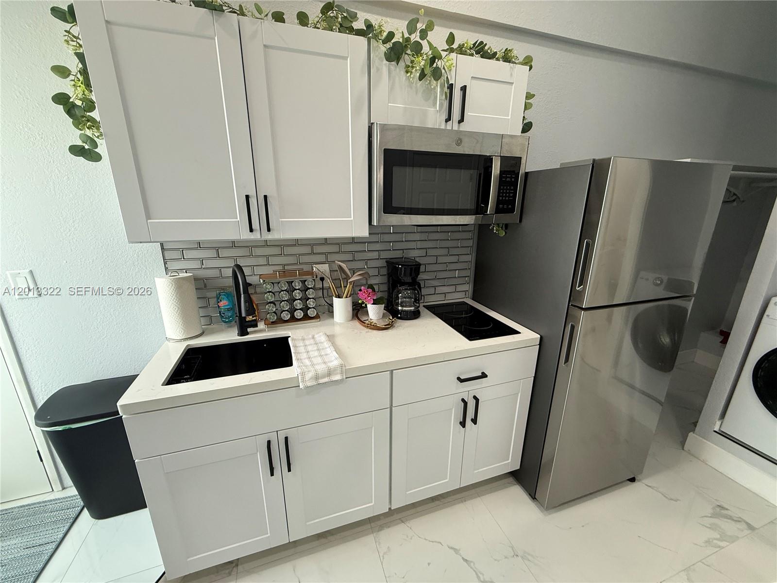 13204 Southwest 228th Street, Unit A Miami, FL 33170 - Photo 1 of 8 a kitchen with white cabinets sink and stainless steel appliances