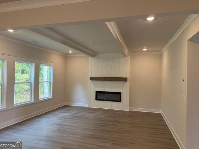 a view of an empty room with window and wooden floor