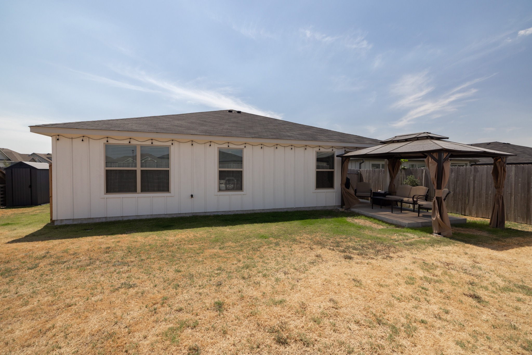 129 Maybelline Road Jarrell, TX 76537 - Photo 26 of 28 An inviting backyard features vertical siding, a spacious lawn, and a cozy covered patio area.