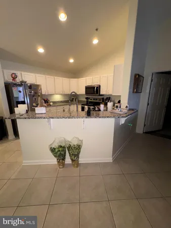 a view of a kitchen with kitchen island stainless steel appliances a sink a stove a microwave a counter top space and cabinets
